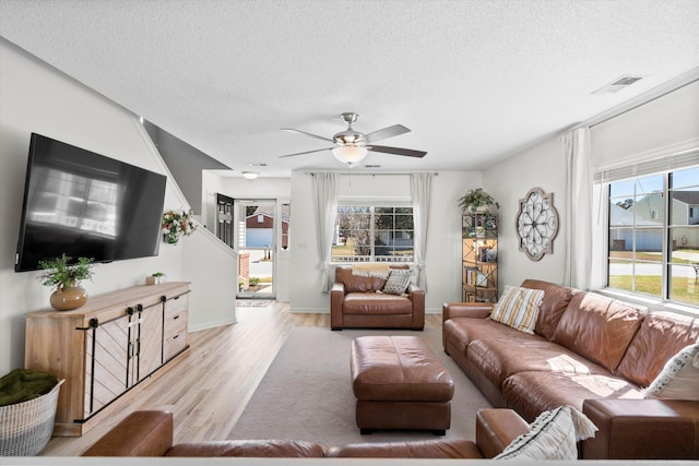 living room with plenty of natural light, light wood-style floors, visible vents, and a textured ceiling