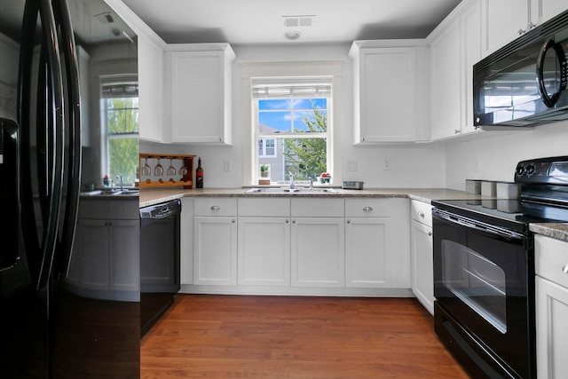 2405 Louisville St, Charleston, SC 29492 - kitchen with a sink, black appliances, wood finished floors, and white cabinetry