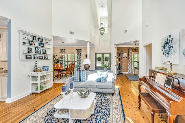living area with an inviting chandelier, light wood-style flooring, and a high ceiling