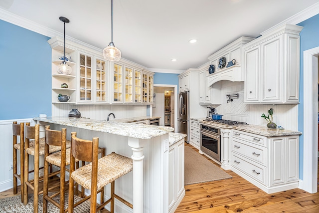 kitchen with a breakfast bar, light wood-style floors, stainless steel appliances, a peninsula, and glass insert cabinets