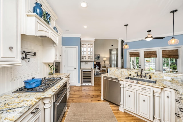 kitchen with ceiling fan, tasteful backsplash, a sink, light wood-style floors, and stainless steel appliances