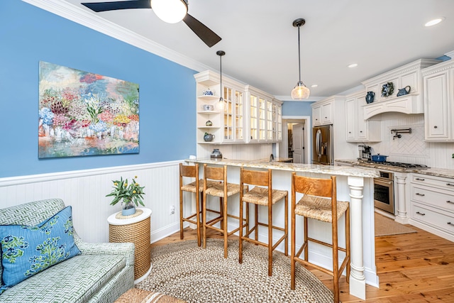 kitchen with a peninsula, a breakfast bar, glass insert cabinets, light wood-type flooring, and stainless steel fridge with ice dispenser