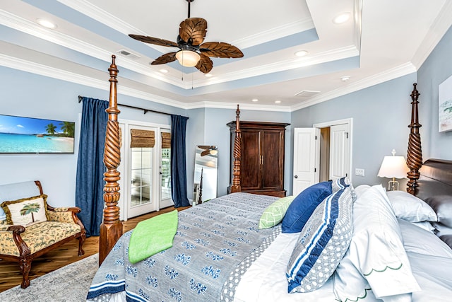 bedroom featuring visible vents, ornamental molding, wood finished floors, and a raised ceiling