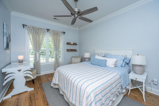bedroom with baseboards, ornamental molding, wood finished floors, and visible vents
