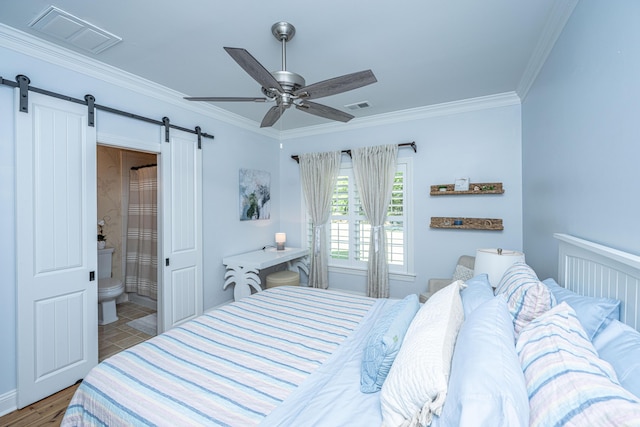 bedroom with ornamental molding, ensuite bath, a barn door, and visible vents