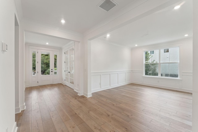 empty room with ornamental molding and light wood-type flooring