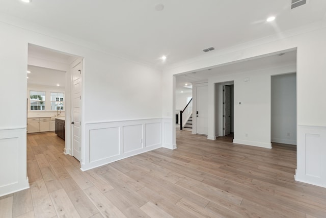 empty room with ornamental molding, light hardwood / wood-style floors, and sink