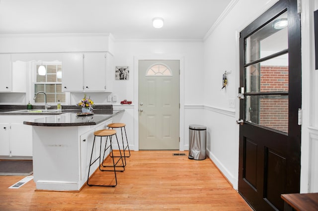 113 Overhill Dr, Walterboro, SC 29488 - kitchen featuring a sink, white cabinets, light wood-style floors, a kitchen breakfast bar, and ornamental molding