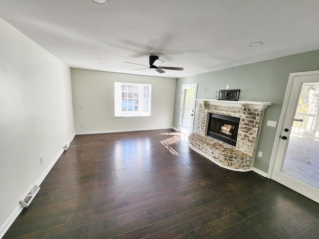 unfurnished living room with a brick fireplace, ceiling fan, and dark wood-type flooring