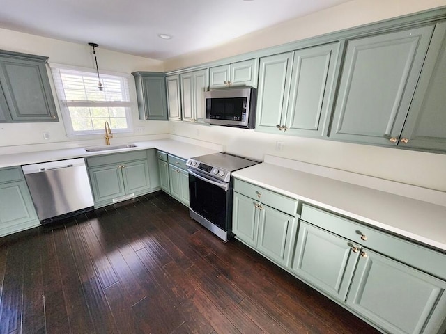 kitchen featuring dark hardwood / wood-style flooring, sink, stainless steel appliances, and hanging light fixtures