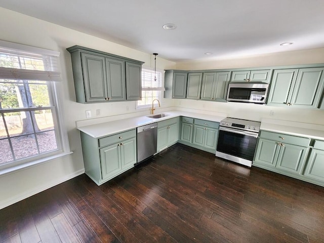 kitchen with sink, hanging light fixtures, dark wood-type flooring, appliances with stainless steel finishes, and green cabinetry