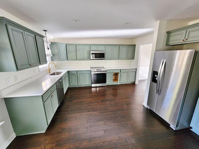 kitchen with appliances with stainless steel finishes, sink, decorative light fixtures, green cabinetry, and dark hardwood / wood-style floors