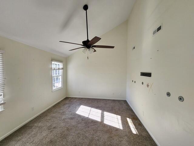 spare room with dark colored carpet, ceiling fan, and lofted ceiling