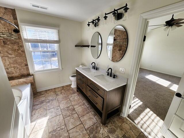 full bathroom featuring vanity, toilet, ceiling fan, and independent shower and bath