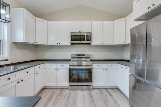306 S Magnolia Ave, Andrews, SC 29510 - kitchen featuring stainless steel appliances, a sink, lofted ceiling, dark countertops, and white cabinets