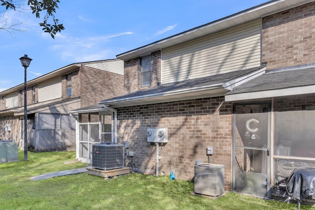 rear view of house featuring cooling unit, a yard, and a sunroom