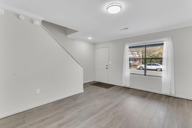 entryway with ornamental molding and light hardwood / wood-style flooring