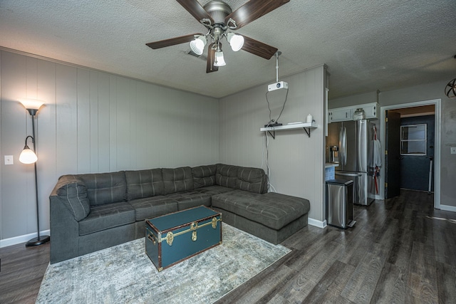 living room featuring ceiling fan, dark hardwood / wood-style flooring, and a textured ceiling