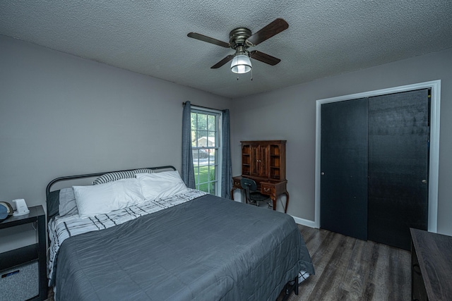 bedroom with ceiling fan, dark hardwood / wood-style flooring, a textured ceiling, and a closet