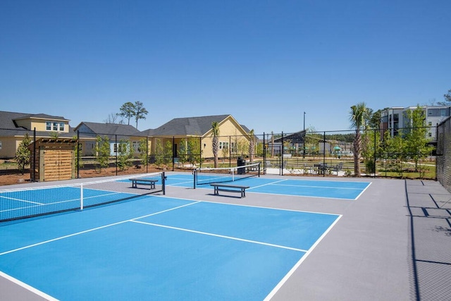view of tennis court featuring fence and a residential view