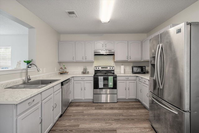 1219 Bradley Blvd, Summerville, SC 29486 - kitchen with appliances with stainless steel finishes, a sink, under cabinet range hood, a textured ceiling, and light countertops