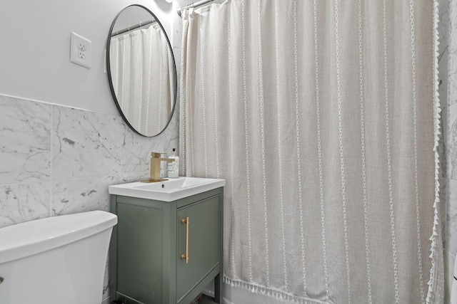 bathroom with toilet, tile walls, and vanity