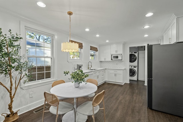 dining space featuring stacked washer / drying machine, dark wood-type flooring, sink, and ornamental molding