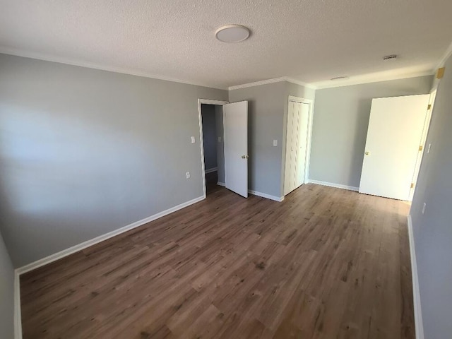 spare room featuring crown molding, a textured ceiling, baseboards, and wood finished floors