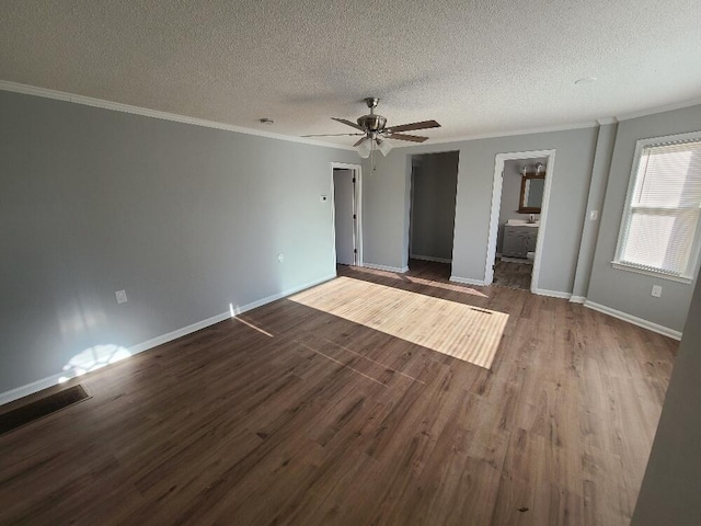 empty room featuring a textured ceiling, visible vents, dark wood finished floors, and crown molding