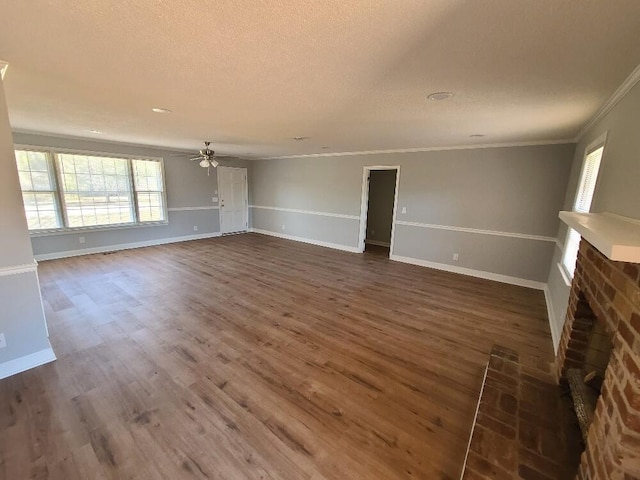 unfurnished living room with a ceiling fan, ornamental molding, dark wood-type flooring, a textured ceiling, and a fireplace