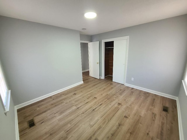 unfurnished bedroom with a closet, visible vents, light wood-style flooring, and baseboards