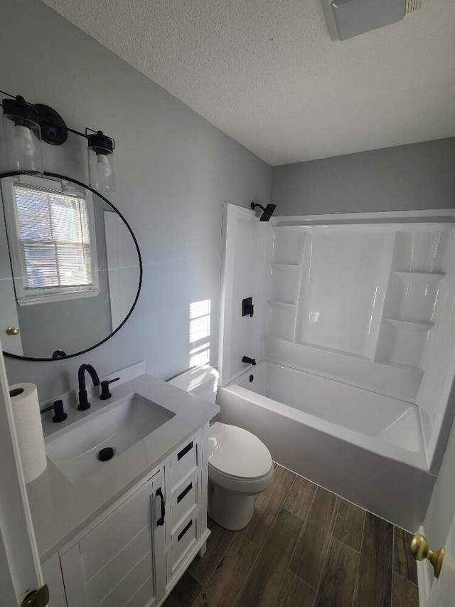 bathroom featuring toilet, tub / shower combination, a textured ceiling, vanity, and wood finish floors