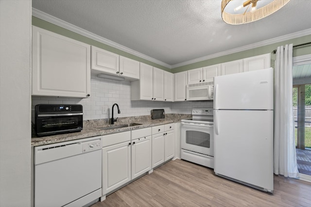 kitchen with white appliances, white cabinets, light wood-type flooring, and a sink