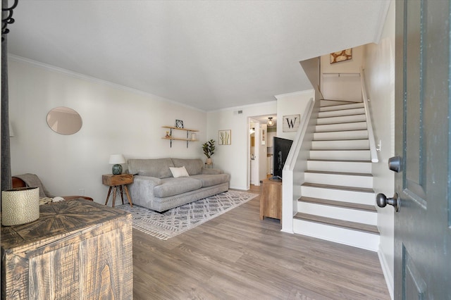 living room featuring stairway, wood finished floors, baseboards, and ornamental molding