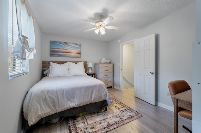 bedroom with light wood-style flooring, baseboards, and ceiling fan