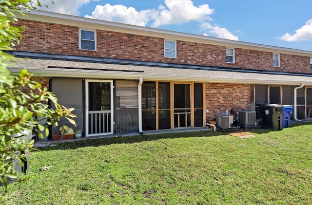 rear view of house featuring brick siding, central air condition unit, and a yard