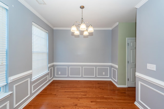 unfurnished room with a chandelier, hardwood / wood-style floors, and crown molding