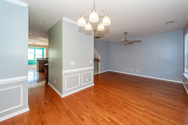 unfurnished living room with wood-type flooring, ceiling fan with notable chandelier, and crown molding