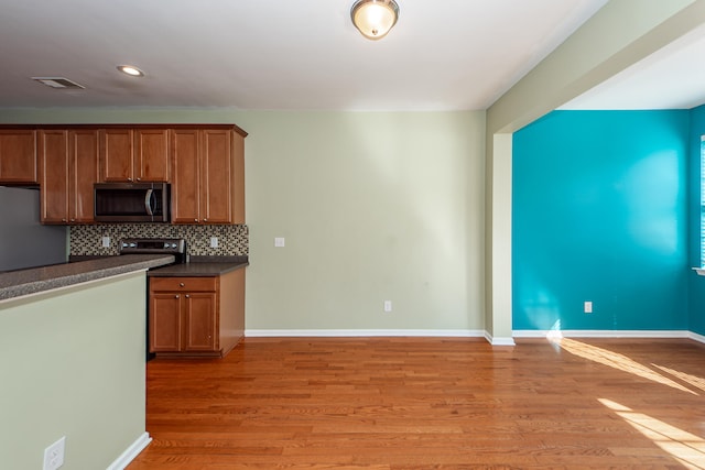 kitchen featuring decorative backsplash, appliances with stainless steel finishes, and light wood-type flooring