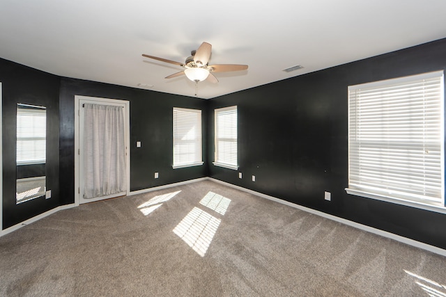 carpeted spare room featuring plenty of natural light and ceiling fan