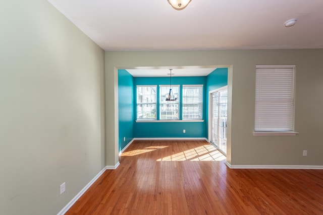 empty room featuring light hardwood / wood-style floors and a notable chandelier