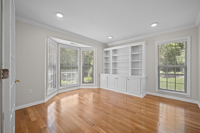 unfurnished room featuring light wood-type flooring, baseboards, and ornamental molding