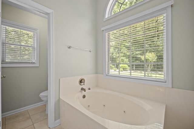 bathroom featuring a jetted tub, toilet, tile patterned flooring, and baseboards