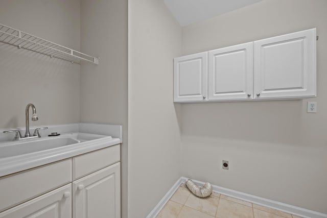 laundry area featuring hookup for an electric dryer, cabinet space, baseboards, and light tile patterned floors