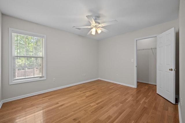 unfurnished bedroom featuring baseboards, light wood-style floors, a spacious closet, and a closet