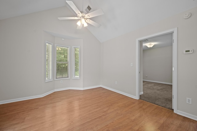 empty room with lofted ceiling, light wood-type flooring, ceiling fan, baseboards, and a smoke detector