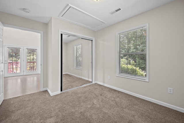 unfurnished bedroom with attic access, carpet flooring, multiple windows, and baseboards