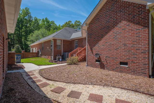 view of side of home featuring crawl space, brick siding, and central air condition unit