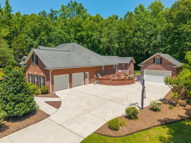 view of front facade with brick siding, concrete driveway, an outbuilding, and a shingled roof