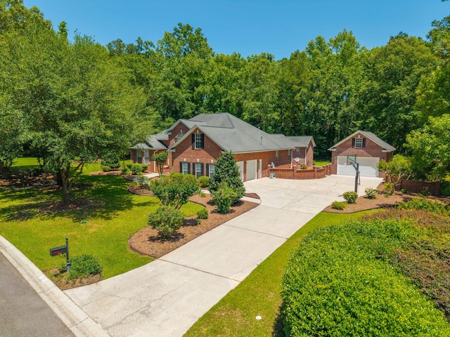 view of front of home featuring concrete driveway, brick siding, a front yard, an outbuilding, and a garage